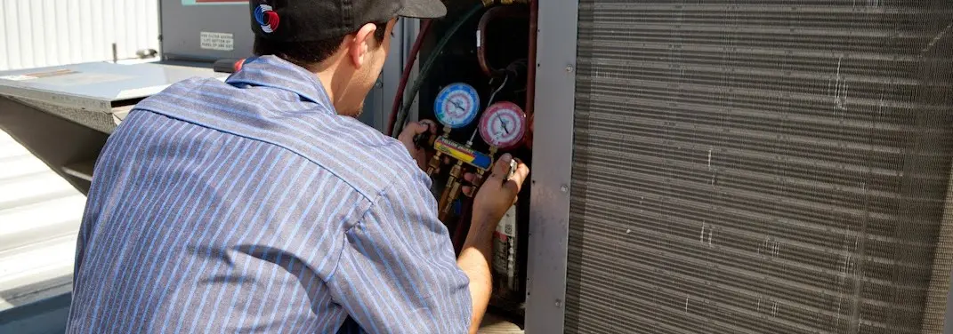 HVAC technician servicing a condenser unit in St. Martin